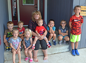 Photo of child care provider Jane Hovey and some of the children she cares for sitting on a front door step.