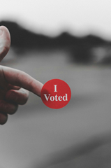 Photo of an "I Voted" sticker, held on a person's pointer finger