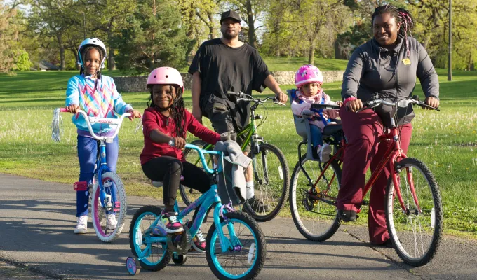 Photo of an African American family on bicycles.