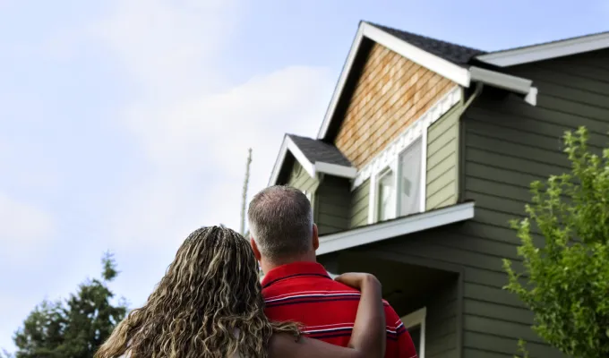 Photo of two adults from behind who are looking up at a house