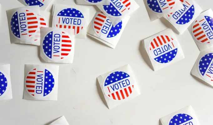 Photo of "I Voted" stickers scattered on a white surface