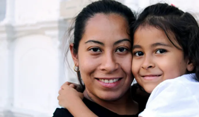Close-up photo of a woman and child, hugging and smiling at the camera