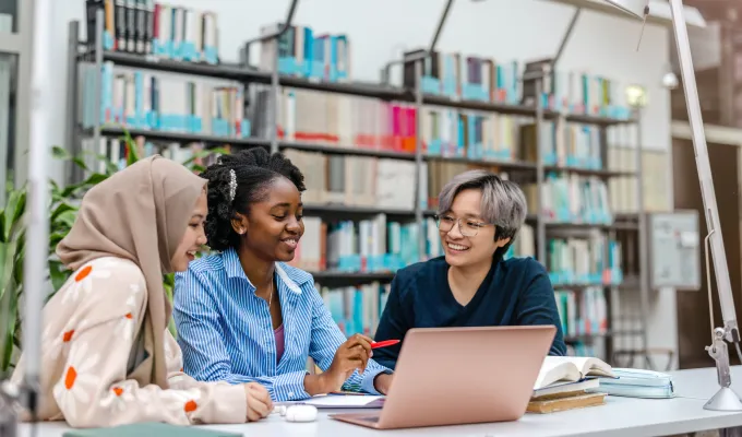 Photo of three women sitting in a library