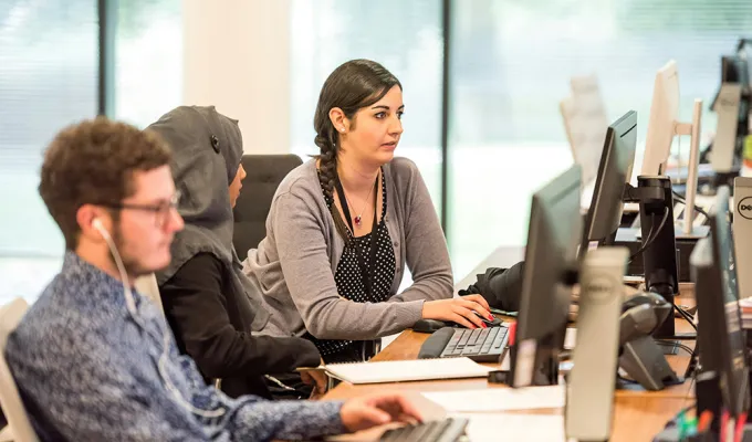 Photo of three adults working at computer screens