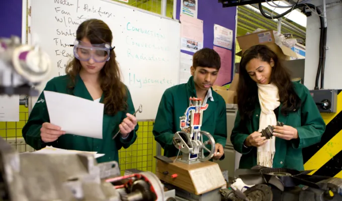 Photo of three young adults working with machinery