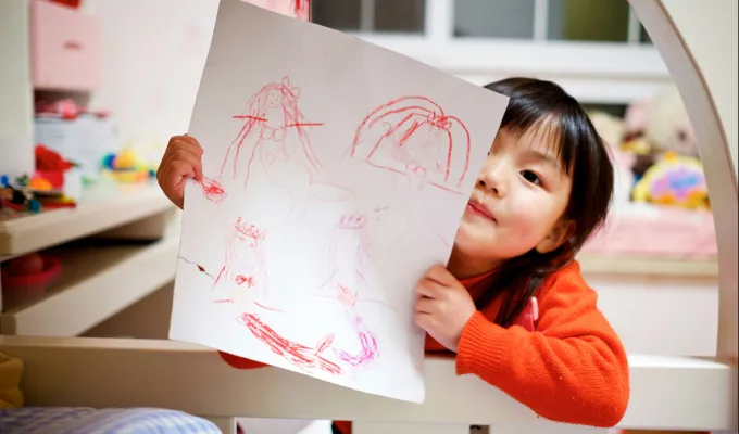 Photo of a young child holding a crayon drawing