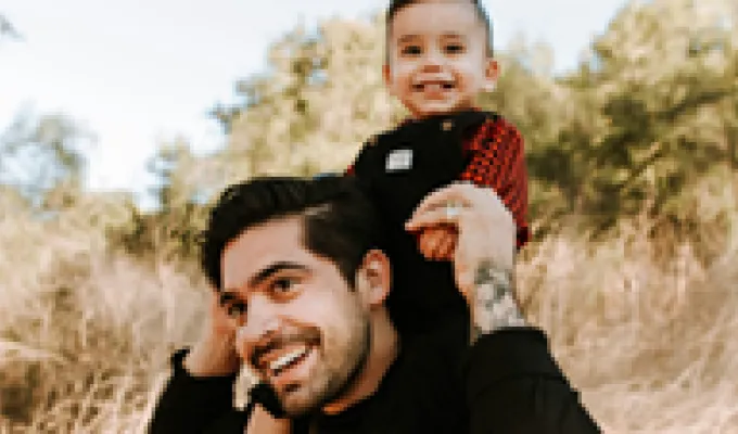 A man carrying a toddler on his shoulders