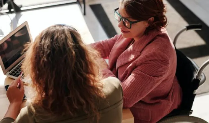 Woman in wheelchair conferring with coworker