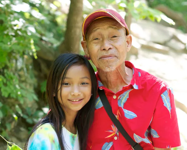 Photo of Asian older man and his pre-teen granddaughter.