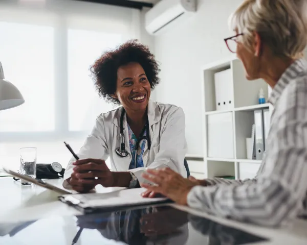 Photo of a smiling health care provider, sitting at a table with her patient