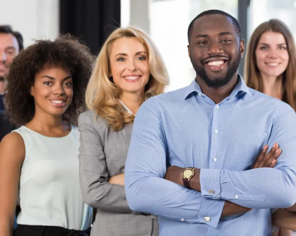 Photo of four diverse professionals standing in a group, smiling at the camera