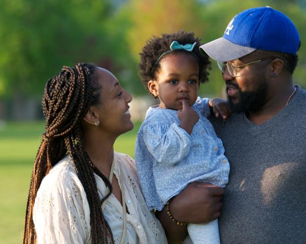 Young black parents, father is holding a little girl who is about two