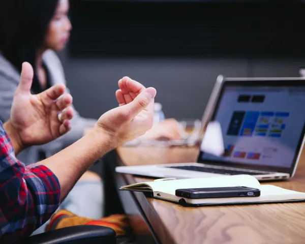 Cropped photo showing hands gesturing in front of a laptop