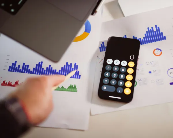 Photo of papers with bar charts and a calculator laying on top