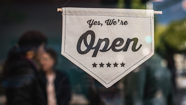 Sign in the window of a small business that says "Yes, we're open." Photo by Tim Mossholder on Unsplash