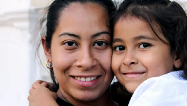 Close-up photo of a woman and child, hugging and smiling at the camera