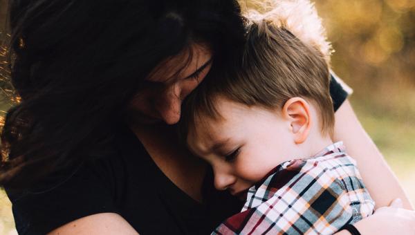 Photo of young mother cuddling her young son. Photo by Jordan Whitt on Unsplash